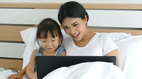 Mother using laptop computer with her daughter Stock Footage 77060557