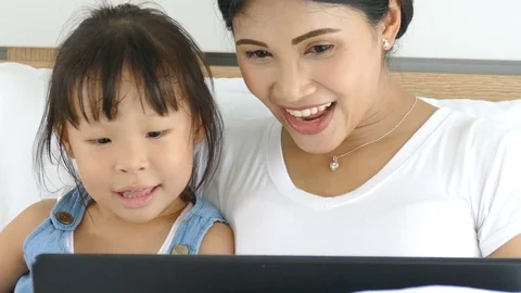Mother using laptop computer with her daughter Stock Footage 77064328