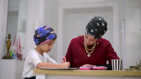 Mother using a laptop while assisting her daughter with schoolwork at home. Stock Footage 140264533