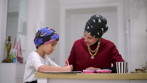 Mother using a laptop while assisting her daughter with schoolwork at home. Stock Footage 140266146