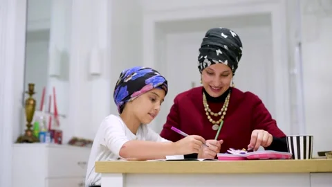 Mother using a laptop while assisting her daughter with schoolwork at home. Stock Footage 140272825