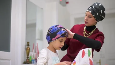 Mother using a laptop while assisting her daughter with schoolwork at home. Stock Footage 140285337