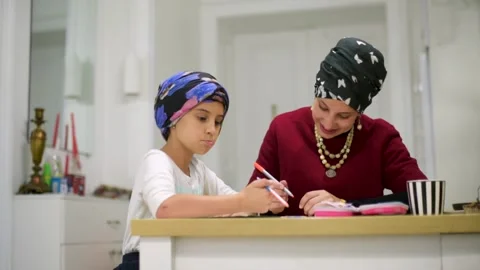 Mother using a laptop while assisting her daughter with schoolwork at home. Stock Footage 140285897