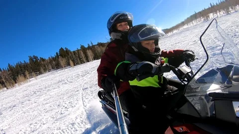 Mother is using selfie stick as her son is driving motor sledge Stock Footage 108941543
