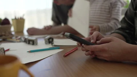 Mother using smart phone while family plays and draws Stock Footage 333261666