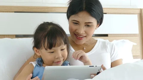 Mother using tablet computer with her daughter Stock Footage 77064186