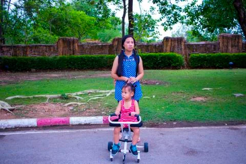 Mother walking while pushing a stroller in the park Stock Photos