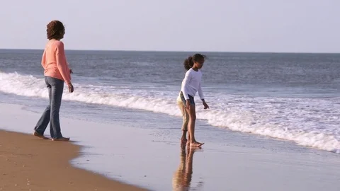 Mother watching daughters playing on beach in ocean waves Stock-Footage 78076026