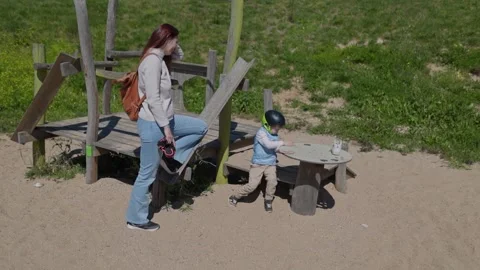 Mother watching her son playing at playground Stock Footage 309867229