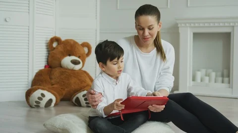 Mother watching her son using digital tablet at home Stock Footage 106309884