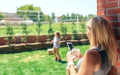 Mother watching mobile while son plays Stock Photos