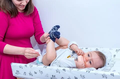 Mother wiping baby's bottom while changing a diaper. Stock Photos