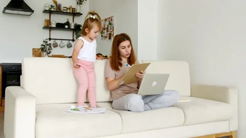 Mother working from home, having a work video call, while her child distracts Stock Footage 164218283