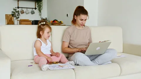 Mother working from home, having a work video call and child playing nearby 스톡 동영상 165317744