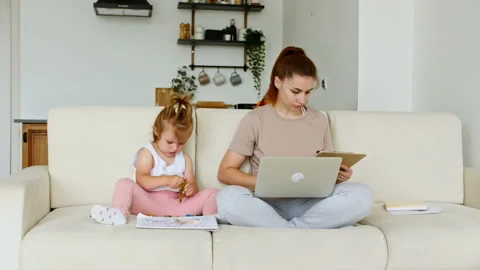 Mother working from home, having a work video call and child playing nearby Stock Footage 165896689