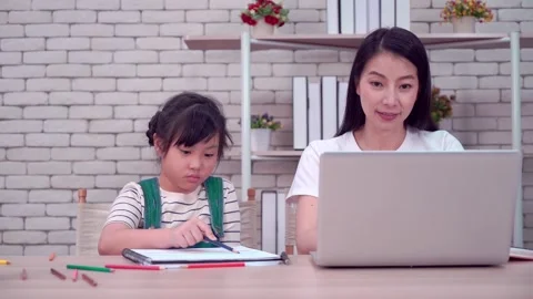 Mother working at home while helping her child doing home school online classes  Stock Footage 161875624