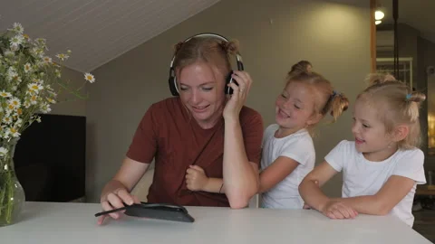 Mother is working remotely home while two naughty little daughters distract her Video stock 145834018