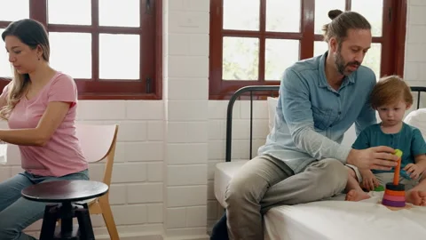 Mother is working while husband and son are sitting in the kitchen. Stock-Footage 239556514