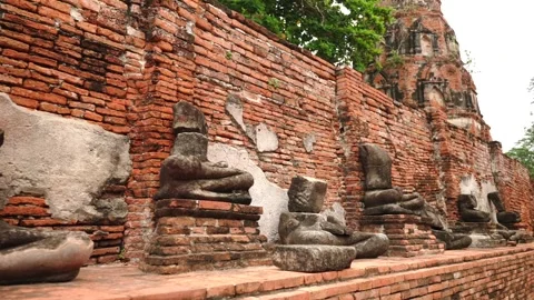 Motion along many ancient headless sitting Buddha statues in a row at Wat Stock Footage 312491220