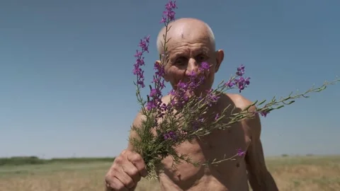 Motion around satisfied old man smelling flowers on field Video stock 201959345