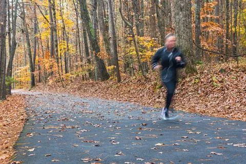 Motion Blur Woman Jogging On Park Trail Amid Fall Foliage Stock Photos