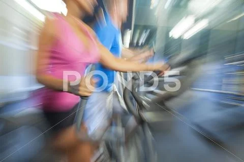 Motion blur zoom man & woman using gym equipment Stock Photos
