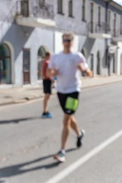 Motion-blurred athletic man running marathon on urban street Фото