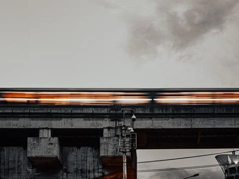 Motion-Blurred BTS Skytrain Passing Over Elevated Concrete Track at Dusk Stock Photos