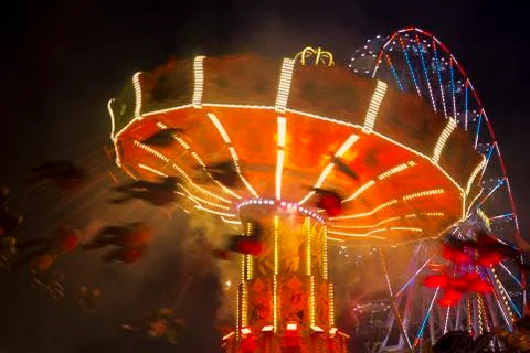 Motion blurred carousel by night with ferris-wheel in the background Stock Photos