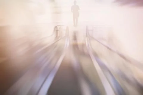 Motion Blurred Image of Man Standing in Front of Escalator. Stock Photos