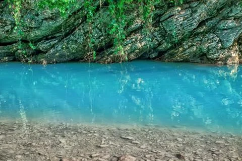 Motion blurred rapids of Khosta River with wet boulders and shore strewn with Stock Photos