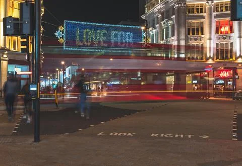 Motion-blurred red double-decker bus at Oxford Circus under Christmas lights Фото