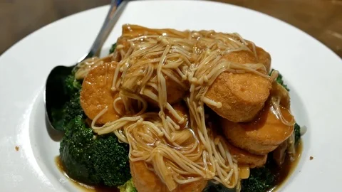 Motion of braised enoki mushroom on egg tofu on table inside restaurant 스톡 동영상 84871859