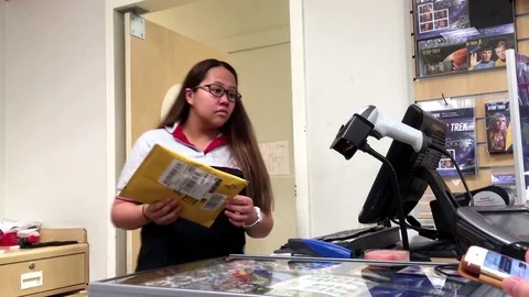 Motion of clerk checking id for customer picking up her parcel at post office Stock Footage 77170396