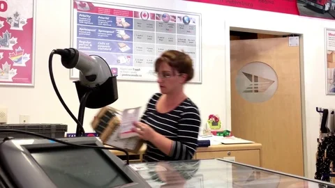Motion of clerk checking id for customer picking up her parcel at post office Stock Footage 77321793