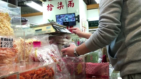 Motion of clerk weighing the candy for customer inside Chinese candy store Stock Footage 73919522