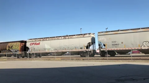 Motion of container freight train passes thru station against blue sky Stock Footage 93531964