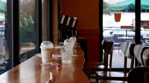 Motion of cups on table with people walking through at Starbucks coffee shop Stock Footage 73104042