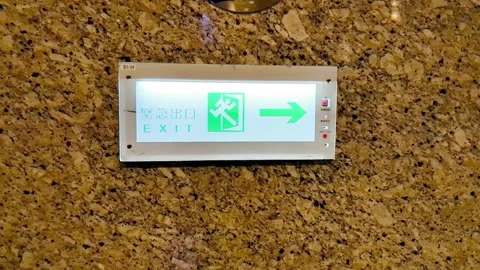 Motion of emergency exit sign on wall inside shopping mall Stock Footage 286343335