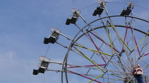 The motion of empty riding Ferris wheel against a blue sky Stock Footage 150530391