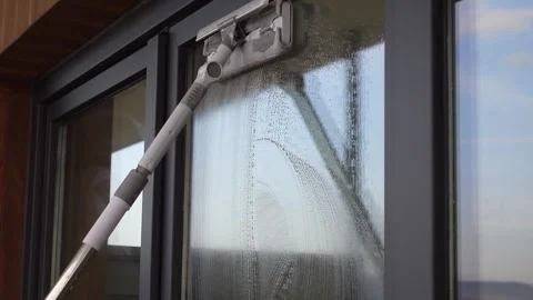 A motion footage showing a window cleaner using squeegee to remove soap sud.. Stock-Footage 333030824