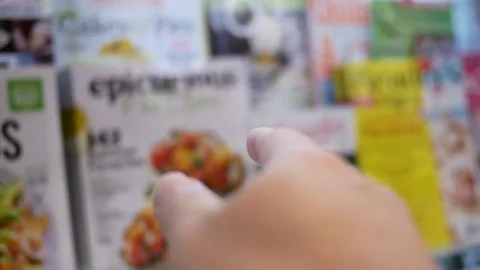 Motion of hand choosing reader's digest magazine at London drugs store Stock Footage 76779437