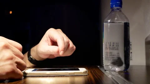 The motion of a man browsing the screen on a smartphone and drinking water Stock Footage 242458189