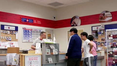 Motion of man mailing parcel at post office inside shopper drug mart store Stock Footage 78111628