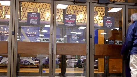 Motion of man opening door and walking through Sears store entrance Stock Footage 70221145