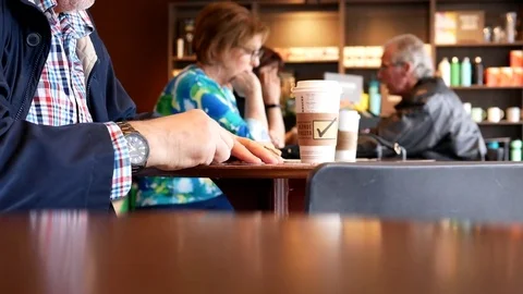 Motion of man scratching lottery ticket inside Starbucks coffee shop Stock Footage 76387705