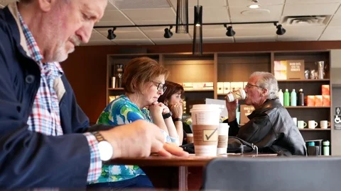 Motion of man scratching lottery ticket inside Starbucks coffee shop 動画素材 83767962