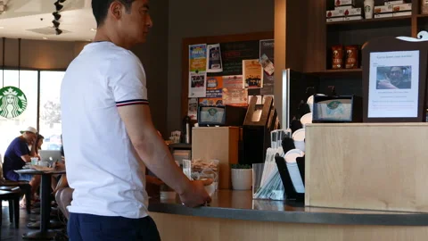 The motion of a man waiting for their coffee inside a Starbucks store Video stock 250456201