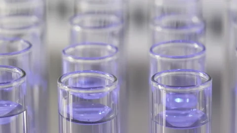 Motion past rows of glass test tubes full of clear liquid Stock Footage 154318970