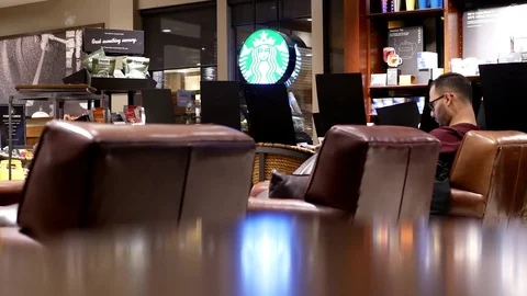 Motion of people drinking coffee and reading book inside Starbucks store Stock Footage 71754107